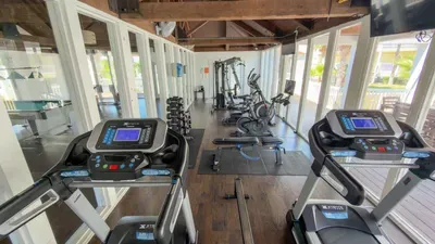 Well‑equipped fitness center featuring treadmills, bikes, ellipticals, weight machines, and free weights, all set in a bright space with large windows and wood‑beam accents—ideal for guests wanting a convenient, energizing workout area.