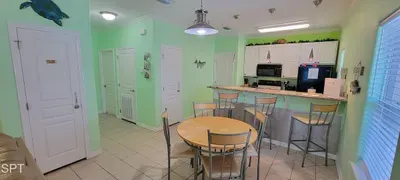 Enjoy meals in this inviting kitchen and dining area featuring a round table, breakfast bar with stools, white cabinetry, and modern appliances. Natural light and tasteful décor make it perfect for cooking, dining, and entertaining.