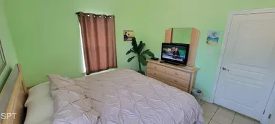 Unwind in this serene bedroom with a plush comfortable bed, warm wooden accents, ceiling fan, and smart TV. Natural light and thoughtful design create a welcoming retreat for restful nights and peaceful mornings.