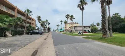 Sunny coastal street lined with swaying palms & relaxed low‑rise buildings offering a peaceful neighborhood vibe just moments from the shoreline. Calm surroundings, easy parking & a breezy tropical atmosphere set the tone for a laid‑back island stay.