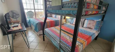 Vibrant Bedroom with Double Bed & Bunk, Colorful Quilts, Natural Light & Patio Access — Perfect for Families and Group Stays