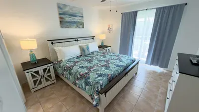Cozy coastal bedroom with a full‑over‑bed design, tropical bedding, and soft blue curtains. A bright, welcoming space perfect for families seeking comfort, convenience, and a fun, beach‑inspired stay.