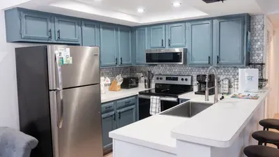 Modern kitchen with blue‑gray cabinetry, stainless appliances, and a bright island workspace. Patterned tile backsplash and thoughtful essentials create a clean, functional space perfect for cooking, gathering, and effortless vacation living.