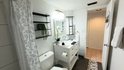 Well‑appointed vanity area featuring a sleek sink, organized toiletries, and soft white towels. Natural accents and warm décor add a soothing feel, creating a bright, refreshing bathroom space that enhances the overall guest experience.