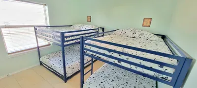 Bright, efficient bunk‑bed room designed for groups and families, featuring two sturdy metal frames, crisp patterned bedding, soft natural light, and simple wall décor—an ideal setup for comfortable, space‑smart stays near the coast.