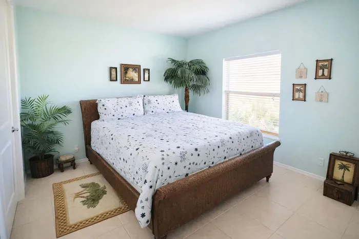 Tropical retreat with serene bed, lush palms, serene pastel walls, natural light, and coastal charm—perfect for a relaxing island escape near the beach. Clean, bright, and thoughtfully styled for your ideal getaway.
