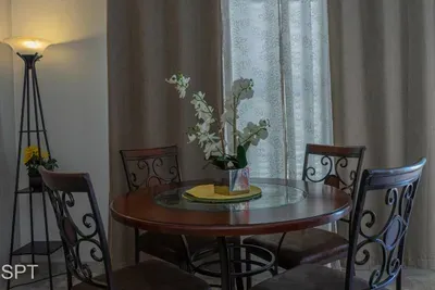 Inviting dining area with a round table, elegant metal chairs, soft lamp lighting, and a fresh floral centerpiece—creating a warm, comfortable space perfect for shared meals, morning coffee, or relaxed gatherings in a cozy, well‑lit setting.