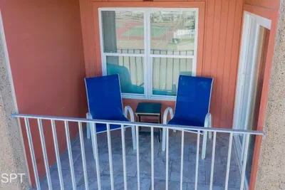 Cozy balcony retreat featuring two cushioned lounge chairs, a sleek side table, warm exterior tones, and a relaxing open‑air setting—perfect for morning coffee, quiet conversations, or unwinding outdoors with fresh coastal breezes.