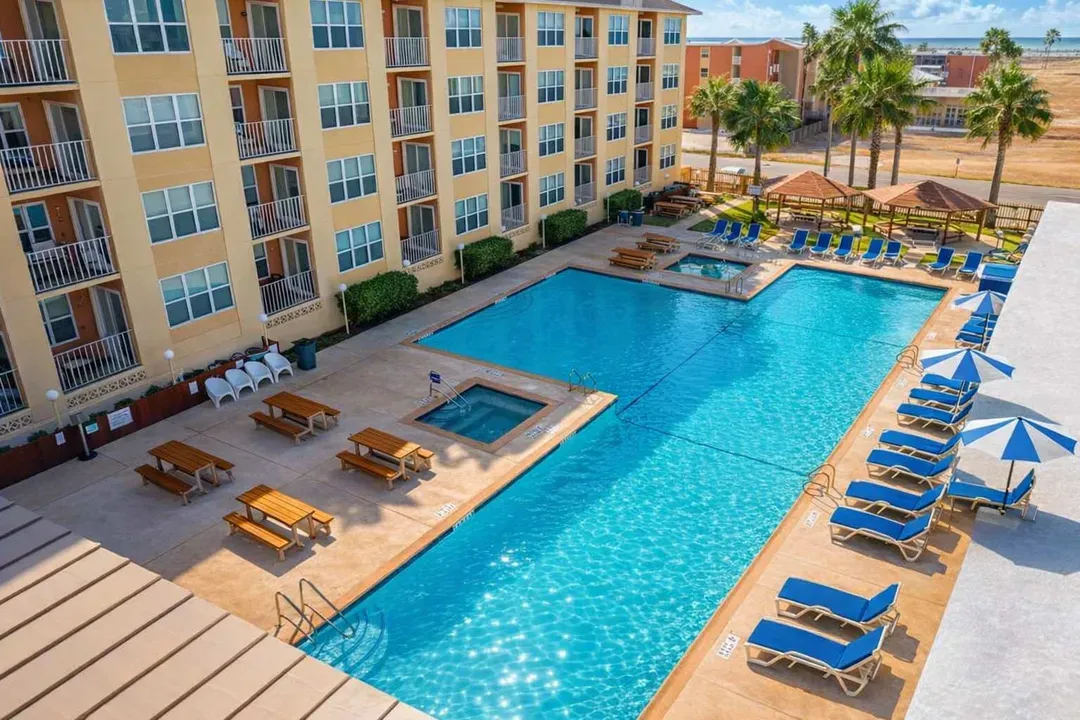 Resort-style condo with sparkling pool, tub, shaded cabanas, picnic tables & palm-lined deck—perfect for family getaways or group retreats just minutes from the beach.