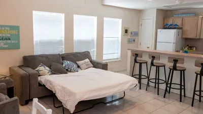 Gather in the bright, airy living space featuring a comfy sofa and a long breakfast bar with stylish stools. Perfect for enjoying morning coffee, quick snacks, or relaxing after beach days in a welcoming, coastal-inspired setting.