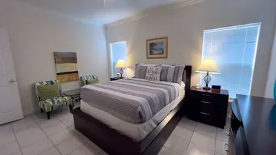 Rest in a tranquil bedroom with blackout blinds, elegant furnishings, and soft coastal accents. Cozy seating, reading lamps, and a plush comfy bed for peaceful nights and relaxing mornings just minutes from the surf and sunshine. Enjoy restful nights
