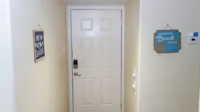 Secure Keyless Entry Doorway
Classic white door with smart lock welcomes guests into this beach-themed entry. "Don't Grow Up" and "Life's a Beach" signs set fun coastal tone; keypad entry ensures easy, contactless access for stress-free arrivals.