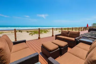 Oceanfront deck with plush seating, panoramic beach views, and resort-style relaxation under sunny skies.