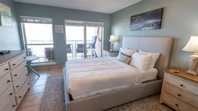 Peaceful coastal bedroom retreat with ocean views framed by glass doors—perfect for unwinding after sun‑filled days. Soft hues, natural light, and a calm seaside vibe create an inviting space that feels effortlessly genuine and serene.