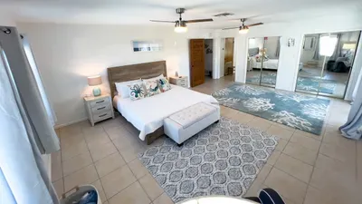 Unwind in the spacious main bedroom with soothing coastal décor, luxe bedding, and abundant natural light. Large mirrored closets, modern fans, and beachy accents provide comfort and style for a dreamy and restful stay.