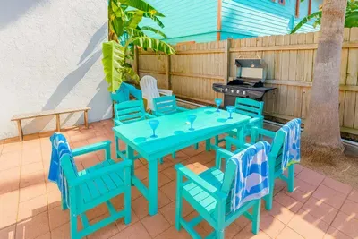 Host the perfect outdoor gathering with a turquoise dining set, grill, and tropical vibe. Shaded by palms, this patio is ideal for alfresco meals, barbecue nights, and drinks with friends. Relax and dine in a fun, cheerful space under sunny skies.