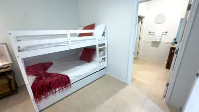 A simple, cozy bunk room designed for easy stays, offering a relaxed spot to unwind after beach days or busy outings. Soft light, clean lines, and a calm flow into the adjoining bath make it an easy, comfortable space for guests to settle in.