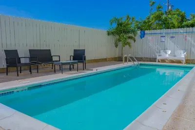 Enjoy outdoor pool area with clear blue water, ample seating, and a sunny, open layout perfect for relaxing or gathering. The fenced setting, shaded spots, and simple modern furnishings create a comfortable, guest‑friendly retreat.