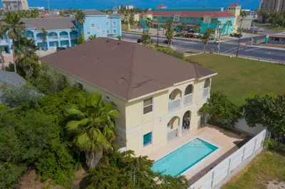 Spacious two‑story retreat with arched balconies, private pool, lush palms, and scenic coastal surroundings. A bright, inviting getaway offering guests comfort, relaxation, and easy access to nearby beaches, dining, and colorful local charm.