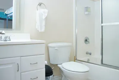 Bright, spotless bathroom featuring a sleek vanity, glass‑door shower, chrome fixtures, and soft neutral tones. A practical, well‑kept space designed for comfort and convenience, offering guests a fresh, reliable setup for daily routines.