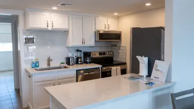 Modern kitchen with stainless steel appliances, dishwasher, microwave, and coffee maker. Ample counter space and bar seating make it perfect for cooking or enjoying casual meals during your stay.
