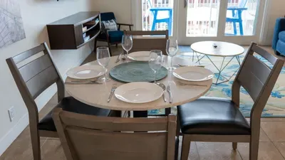 Cozy dining area with seating for four, set with dinnerware and wine glasses. Perfect for enjoying meals together, game nights, or casual gatherings. Bright and inviting, it flows seamlessly with the living space in your South Padre Island condo.