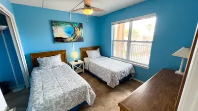 Bright and airy twin bedroom with cozy floral bedding and natural light. Ideal for friends or family sharing space, this room offers comfort and calm with a refreshing coastal vibe.
