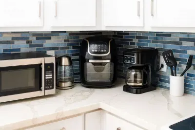 Cook with ease in this fully equipped kitchen—microwave, air fryer, coffee maker, kettle, and utensils await against stylish blue tile. Enjoy all the comforts for homemade meals or quick snacks before hitting the beach!