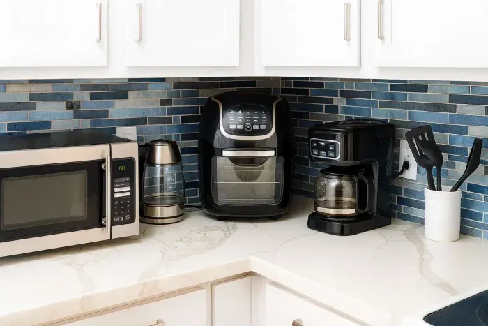 Cook with ease in this fully equipped kitchen—microwave, air fryer, coffee maker, kettle, and utensils await against stylish blue tile. Enjoy all the comforts for homemade meals or quick snacks before hitting the beach!