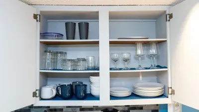 Stocked kitchen cabinets with a full set of glassware, mugs, plates, and bowls ready for dining and entertaining. Everything needed to enjoy meals in style during your coastal getaway.