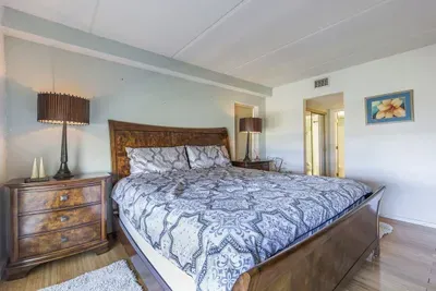 Rest in this warmly appointed bedroom featuring a classic wooden bed, soft patterned linens, matching nightstands, and ambient lighting—creating a calm, inviting retreat ideal for unwinding after sun‑filled coastal days.