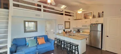 Settle into a bright open‑concept living space with a granite island, stainless appliances, cozy sofa seating, and a sleek smart TV setup. Perfect for cooking, relaxing, and enjoying a comfortable, well‑designed home base during your stay.