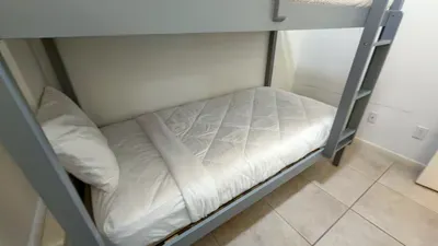 Fun Bunk Bed Nook
Twin-over-twin gray bunk beds offer cozy sleeps for kids or extra guests in this compact, bright space. Crisp white linens and tiled floors keep it fresh—ideal for family beach vacations!