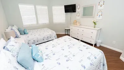 A calm, coastal‑themed room with soft patterns and twin beds that feel welcoming and easy to settle into. Gentle light, clean lines, and a relaxed layout create a soothing space perfect for unwinding after long, sun‑filled days.