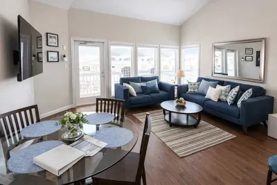 Sun‑filled living and dining space with coastal charm — soft blues, warm wood, and natural light create a relaxed, welcoming vibe perfect for unwinding after beach days or sharing easy meals with family and friends.