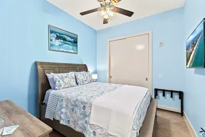 A calm, coastal bedroom with soft blue tones, simple décor, and an easy, welcoming layout. The space feels bright and unhurried, offering a relaxed spot to settle in and unwind with a clean, comfortable vibe that stays warm and inviting throughout.