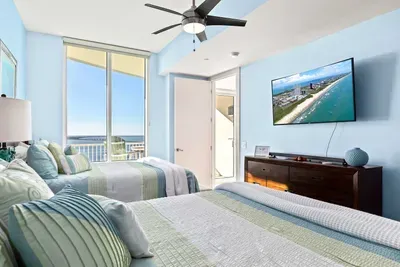 A bright, coastal bedroom with soft blue walls, twin beds, and plenty of natural light that keeps the space feeling open and relaxed. The calm layout and clean styling create an easy, welcoming atmosphere that stays comfortable throughout the stay.