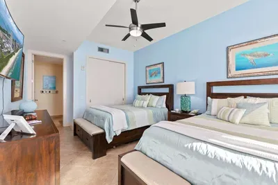 A bright, coastal bedroom with twin beds, soft blue tones, and a clean, easygoing layout that feels relaxed and welcoming. The simple styling and calm atmosphere create a comfortable space that keeps the vibe warm, balanced and effortless throughout.