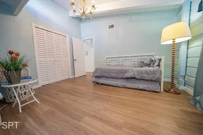 Bright, cottage‑coastal bedroom featuring a cozy daybed, vaulted ceilings, soft blue walls, and warm wood floors. A charming reading nook, natural light, and relaxed décor create a peaceful space perfect for quiet mornings and restful evenings.