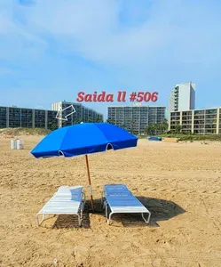 Beachfront setup with loungers and a shaded umbrella on soft sand, backed by resort‑style towers and open shoreline views. The bright, coastal setting creates a guest‑ready space perfect for relaxing, unwinding, and enjoying easy access to the beach.