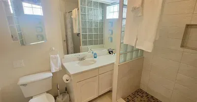 Bright, modern bathroom with a spacious walk‑in shower, clean tile finishes and natural light. Designed for comfort and convenience with fresh, functional amenities.