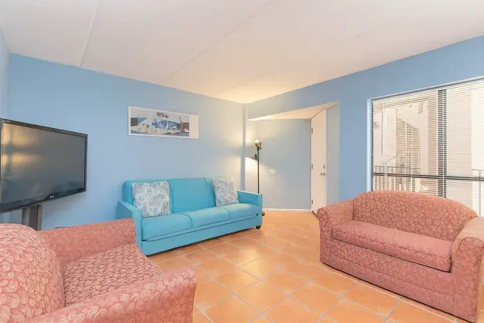 Bright Coastal Living Room | Steps to Beach & Balcony Views
Relax in this vibrant living room with turquoise sofa, red accent chairs & terracotta tile floors. Enjoy natural light, smart TV & balcony views.
