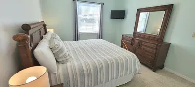 Calming bedroom sanctuary featuring soft neutral tones, warm bedside lamps, a wood headboard, and cozy striped bedding. Designed to offer guests a restful, inviting atmosphere ideal for quiet evenings and refreshed mornings.