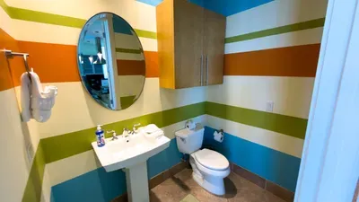 A bright, playful bathroom with bold stripes and a clean, simple layout that keeps the space feeling fresh and inviting. The cheerful colors and uncluttered design create an easy, upbeat atmosphere that adds a light, relaxed touch to the stay.