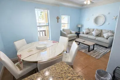 Coastal-chic living & dining with marble-top table, plush seating, sea-inspired decor, and natural light—perfect for relaxing or entertaining in a breezy beachside retreat.