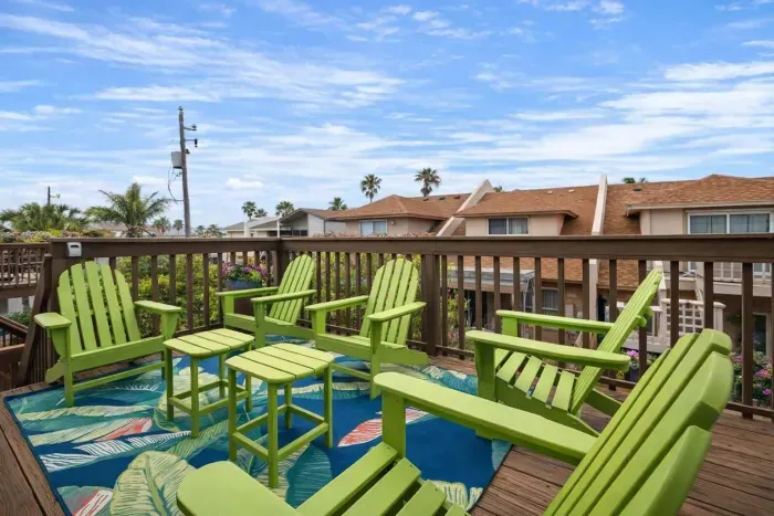 Tropical deck retreat with 6 vibrant Adirondack chairs, lush palm views, and colorful rug—perfect for morning coffee or sunset chats in a coastal neighborhood. Relax, unwind, and soak in the beachside vibes.