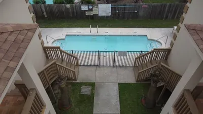 A sunny, well‑kept pool area framed by palm‑lined walkways and tidy buildings offers guests a refreshing place to relax. Clear blue water, open spaces, and a calm coastal setting create an inviting spot to unwind and enjoy warm, easygoing days.