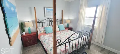 Bright and inviting primary bedroom featuring a wrought‑iron canopy bed, floral linens, turquoise accents, and abundant natural light — a relaxing retreat designed for comfort and style.
