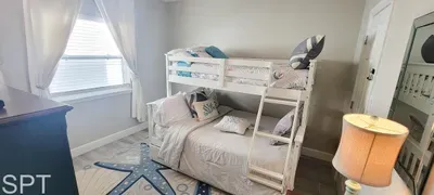 Cozy coastal bunk room with bright décor, soft bedding, and beach‑inspired accents — a welcoming, family‑friendly space perfect for kids or extra guests.
