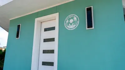 Vibrant exterior with modern entryway, sleek white door, and bold turquoise façade. A bright, welcoming arrival point that sets the tone for a comfortable stay.